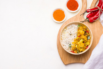 Aloo gobi Indian vegetarian vegetable dish on a wooden chopping board. Copy space
