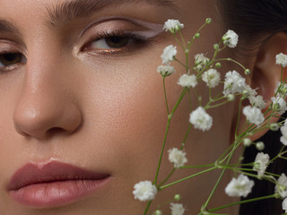 Close up half portrait of a face with beautiful skin and nude makeup, eyeliner and long eyelashes,...