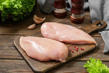 Raw chicken breast fillet on a wooden Board on a brown wooden table