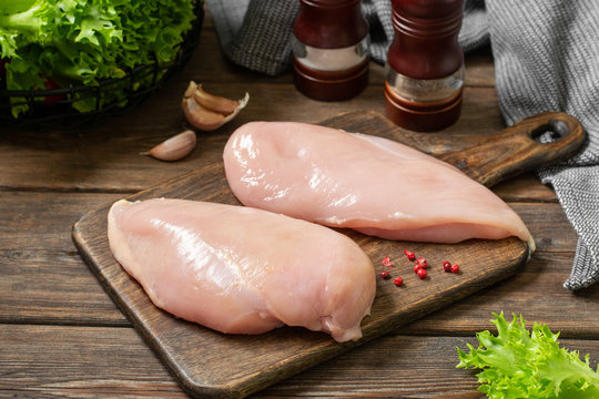 Raw Chicken Breast Fillet On A Wooden Board On A Brown Wooden Table