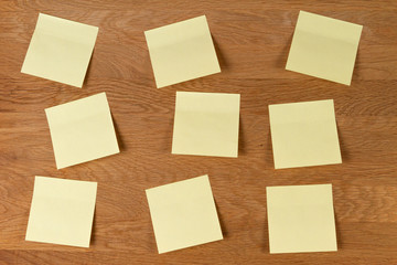 Sticky notes. Blank yellow square paper stickers on natural wooden board background