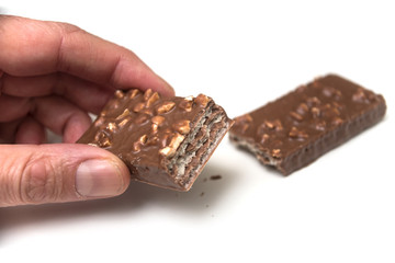 Closeup of chocolate bar with nuts in hand on white background