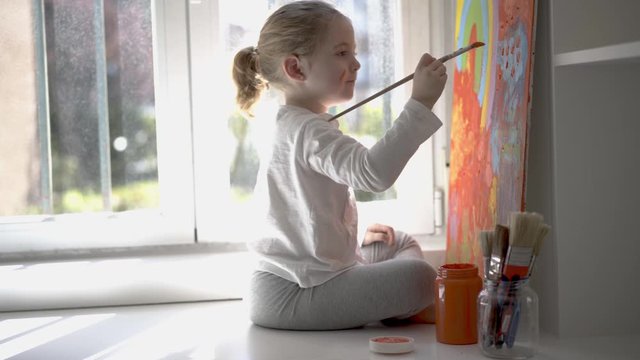 Little girl painting picture with paintbrush