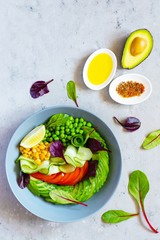 Healthy vegetarian food. Fresh vegetables cucumber, tomato, corn, green peas, avocado, lettuce in a bowl on a blue background. Healthy eating concept.