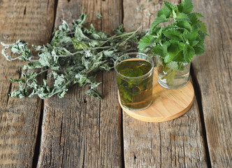 Medicinal herbal tea using dried Melissa. Dried leaves of Melissa or mint with a fresh twig and decoction in a glass on an wooden table.