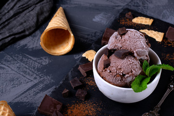 Chocolate ice cream with chocolate pieces with frost and mint on ceramic bowl