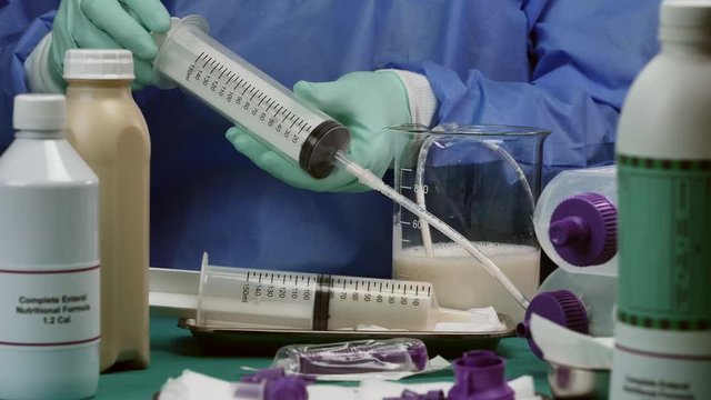 Nurse extracts enteral nutrition content with syringe, pailative care in a hospital