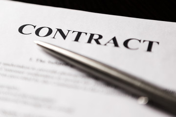 Close-up of word contract with silver pen. Selective focus.