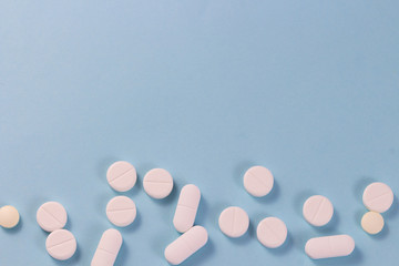 White pills on a blue background are located below. Photo from above. Copy for text.