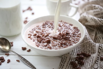 Milk is poured into chocolate balls.
Breakfast cereal