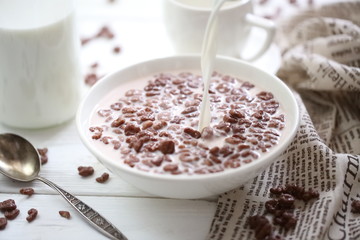 Milk is poured into chocolate balls.
Breakfast cereal