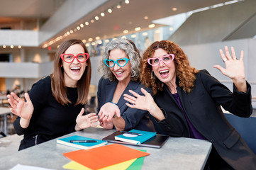 three business women having a meeting and wearing heart shaped glasses