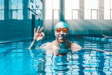Portrait of a man in the pool. He is wearing huge funny glasses. Water sports concept.