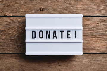 a donate sign on a wood table