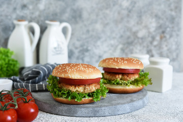 Hamburger with sauce and vegetables on a concrete table. Fast food.