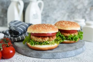 Hamburger with sauce and vegetables on a concrete table. Fast food.
