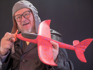 Portrait of strange elderly man has red airplane in his hands and torque spinner of apropeller....