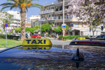 Black taxi cars with yellow standard signs on top parked or stoped on busy city street, taxi service.