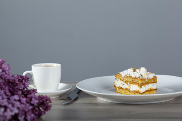 cake on the plate and cup of coffee with lilac