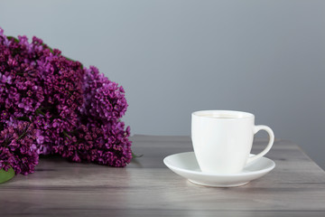 cup of coffee and lilac on table