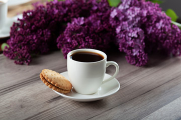 cup of coffee and lilac on table