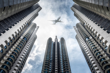 Urban skyline with passenger plane flying over business skyscrapers, high-rise office buildings