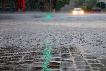 Heavy rain at the crossroads and the green light of a traffic light were reflected in large drops...