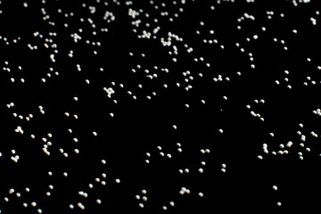 white confectionery sprinkle in the form of balls on a black background