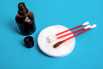 Jar with medical iodine and cotton buds on blue background