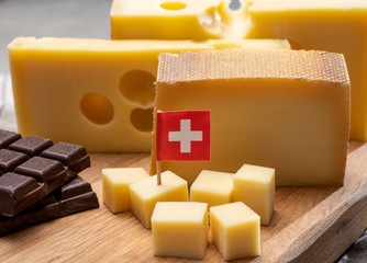 Tasty Swiss food, block of medium-hard yellow cheese emmental or emmentaler with round holes,...