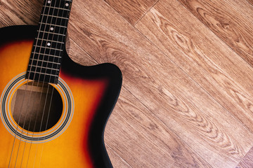 Yellow acoustic guitar on a wooden background