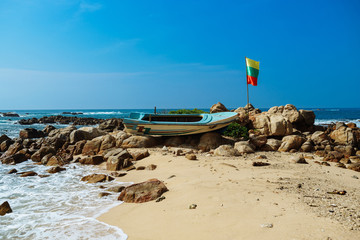 Old boat with flag on secret beach, Sri lanka