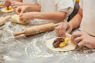 young children fill a flour product with a sweet filling. Master class baking
