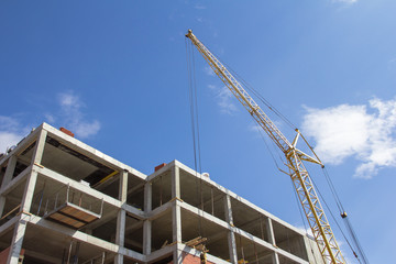 Fototapeta na wymiar Construction technologies. Construction of a building made of reinforced concrete and a construction crane against the blue sky
