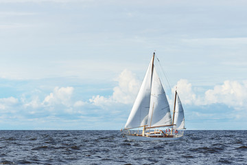 Old expensive vintage wooden sailboat (yawl) close-up, sailing in an open sea. Dramatic cloudscape....