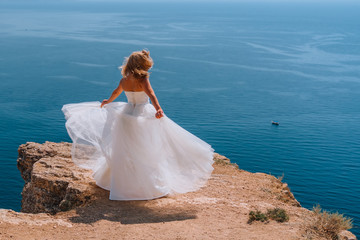 Fototapeta na wymiar Happy beautiful bride in wedding dress whirls and dances on ocean beach. Concept wedding day. Fiolent Crimea