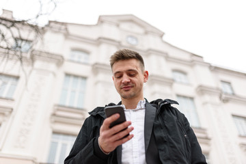 Happy young man with his smartphone outdoors