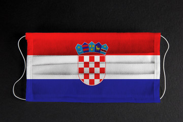 Coronavirus covid pandemic in Croatia. Flag of  Croatia printed on medical mask on black background. National healthcare system concept. Covid-19 outbreak, quarantine in Zagreb, Croatia