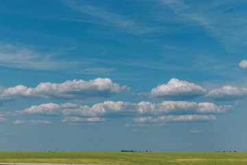 Blue sky with clouds and green field