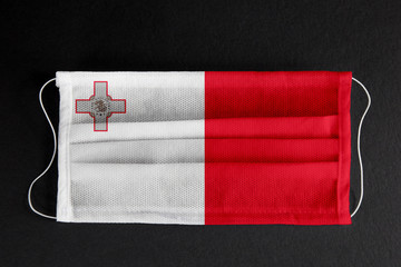 Coronavirus covid pandemic in Malta. Flag of Malta printed on medical mask on black background. National healthcare system concept. Covid-19 outbreak, quarantine in Valletta, Malta.