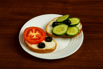 White plate with assorted sandwiches on a wooden table.