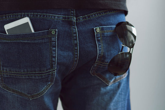 Phone and sunglasses in jeans pocket