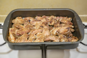 Fresh appetizing chicken wings fried on a kitchen gas stove