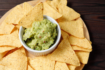 Mexican avocado sauce guacamole with nachos on a wooden background