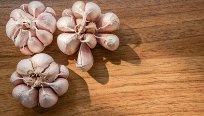 Garlics on wood table background with natural light,Garlic is a spice that gives the smell and taste to food,Also helps to reduce cholesterol in the blood,Control sugar levels in people with diabetes.