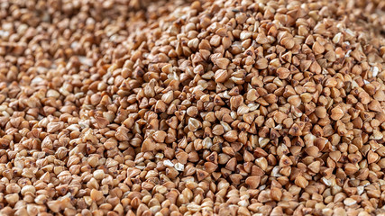Essential goods: Buckwheat. Buckwheat seed pour in bunch closeup. Buckwheat cereal background.