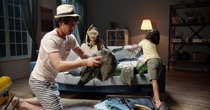 Young mom wearing scuba diver mask is meditating on couch while her husband and child are packing clothes into suitcase, setting mentality for a vacation - happy family 4k footage