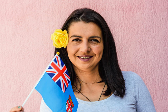 Woman holds flag of Fiji in front of isolated wall background