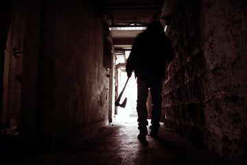 Silhouette of Man holding Axe. Hatchet in Arm in dark Hallway. Scary homicide scenes