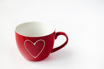 Red cup with white heart on  white background. Soft focus.